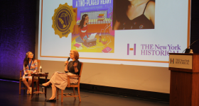 Author Doan Phuong Nguyen and DiMenna Children's History Museum Vice President & Director Alice Stevenson  sit on a stage in conversation about Doan Phuong's NY Historical Children's Book Prize winning title, A Two-Placed Heart.